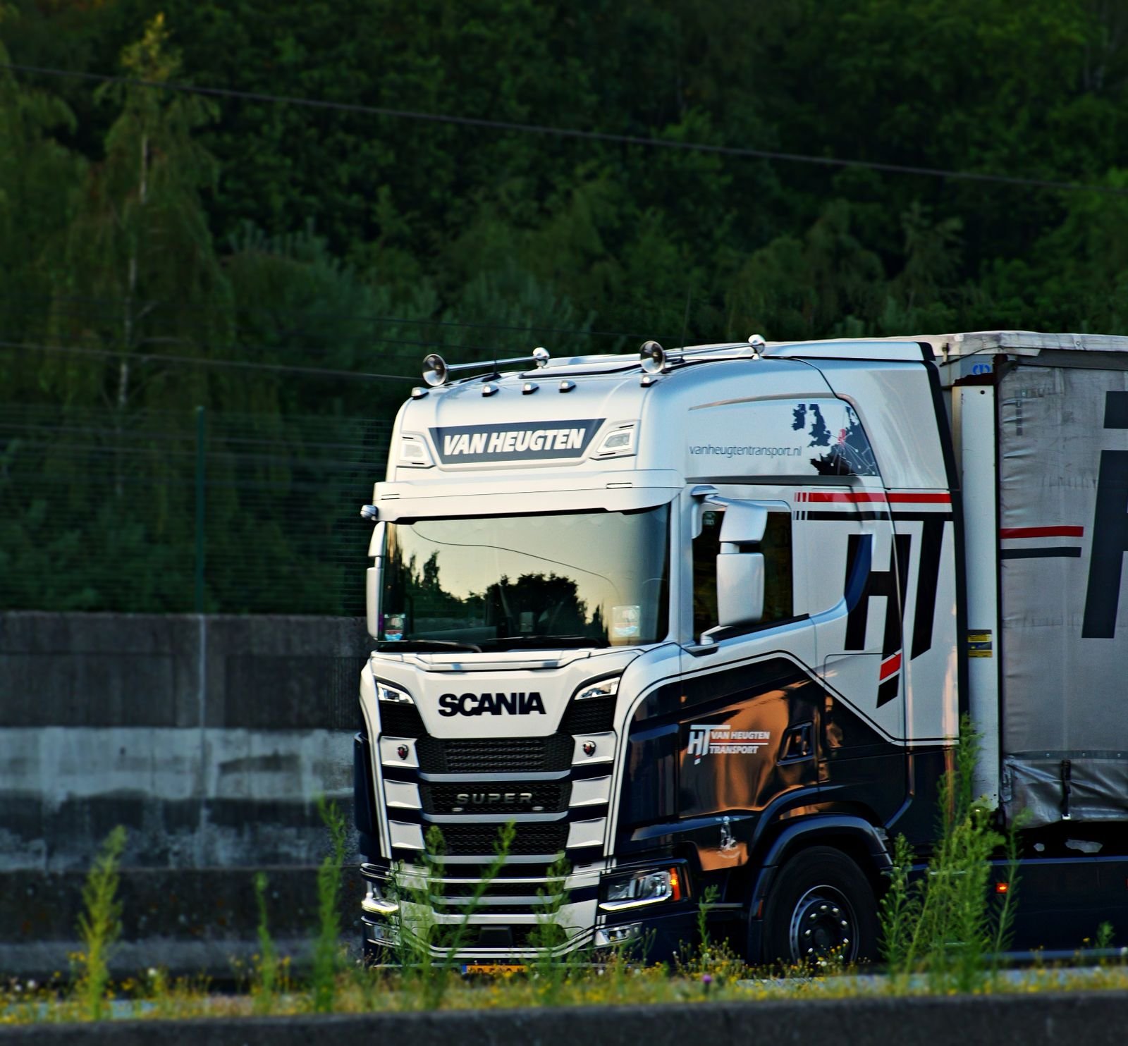 A white Scania tractor unit coupled to a curtain-side trailer