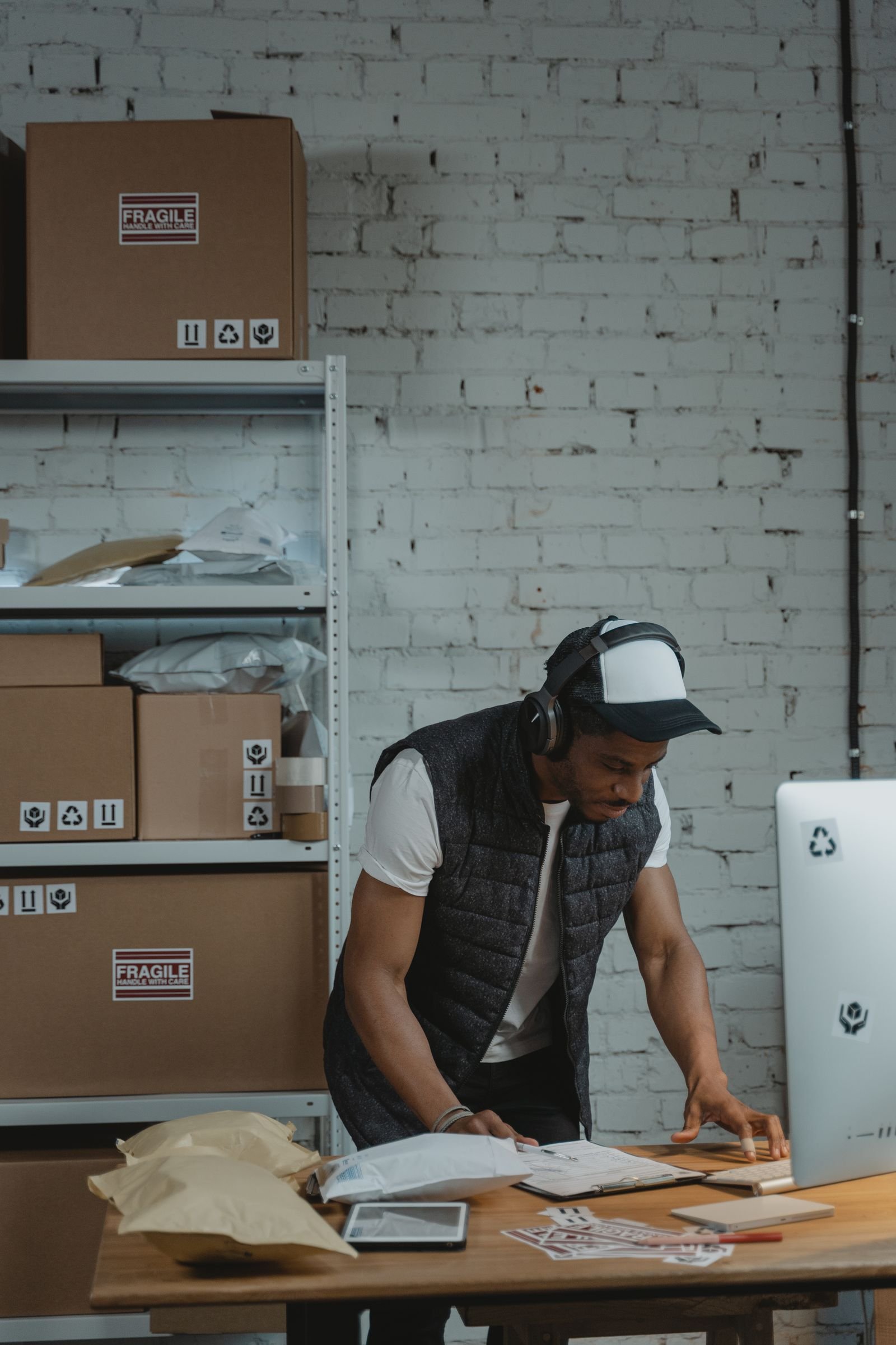 A dispatch coordinator working at a computer among shelved parcels